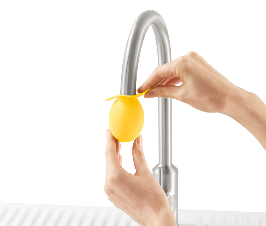 Femme fixant un embout détartrant jaune pour robinet sur un robinet d'évier.