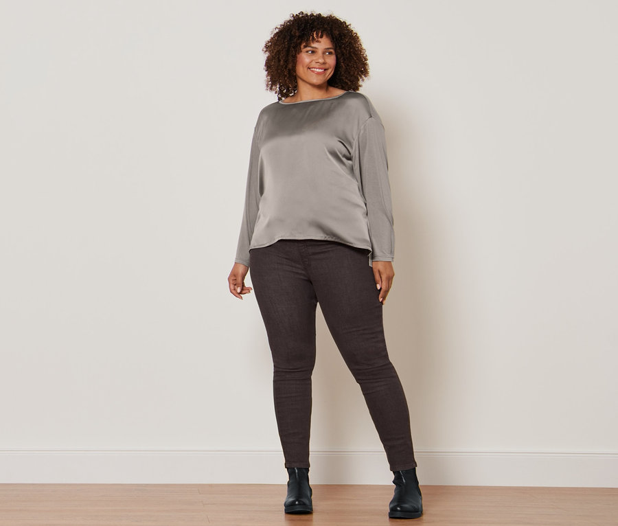 Femme posant en blouse bimatière, tregging marron foncé et bottines en cuir.