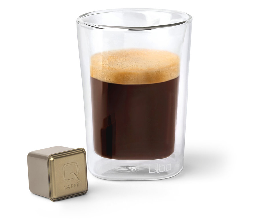 Une capsule de café Qbo Caffè JABANA YIRGA à côté d'un verre de café.