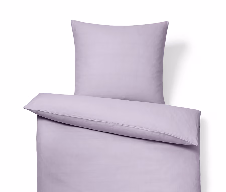Un ensemble de linge de lit lilas en lin lavé : drap-housse, oreiller et couette.