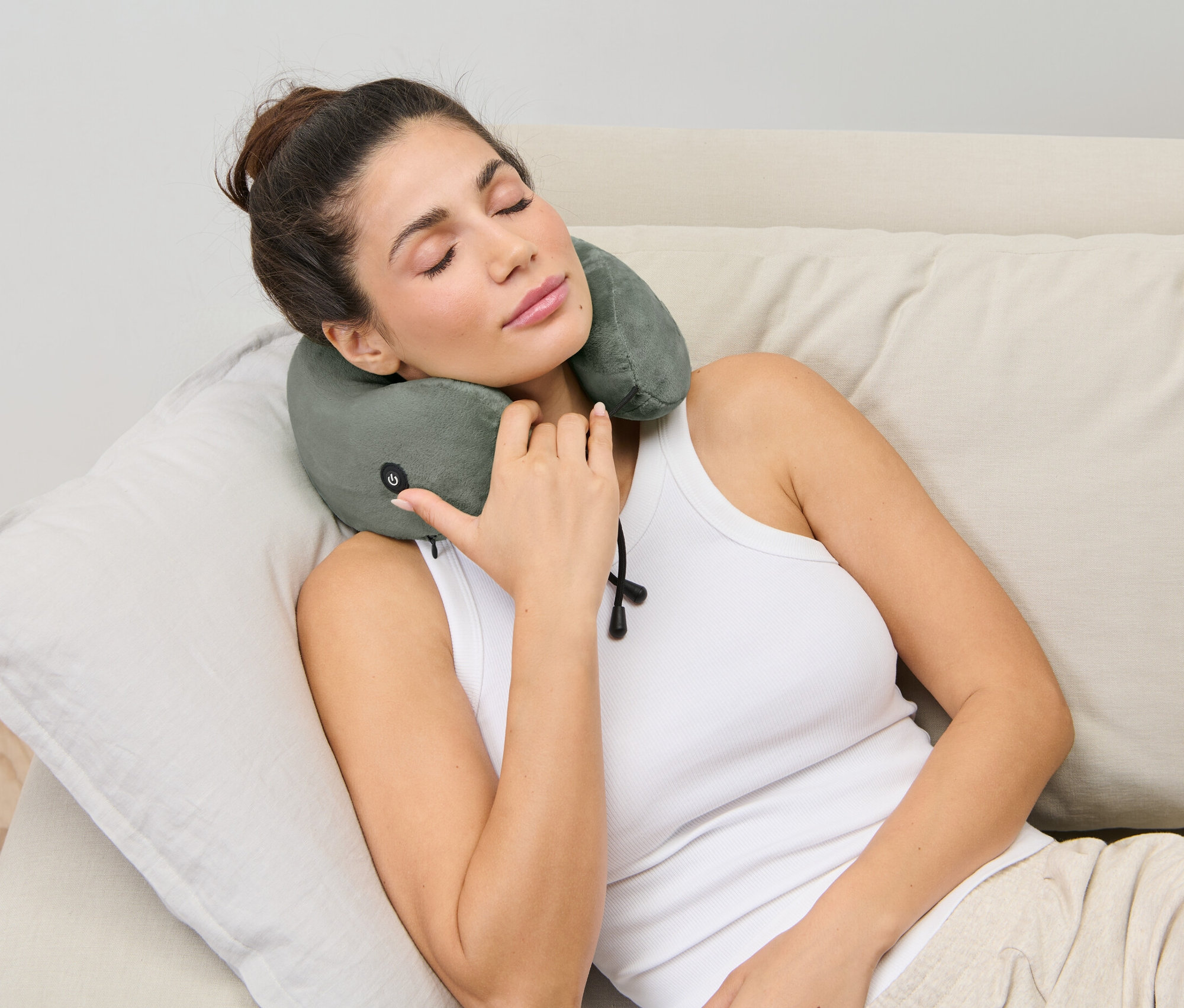 Une femme est allongée sur un canapé avec un coussin de nuque avec massage par vibrations.