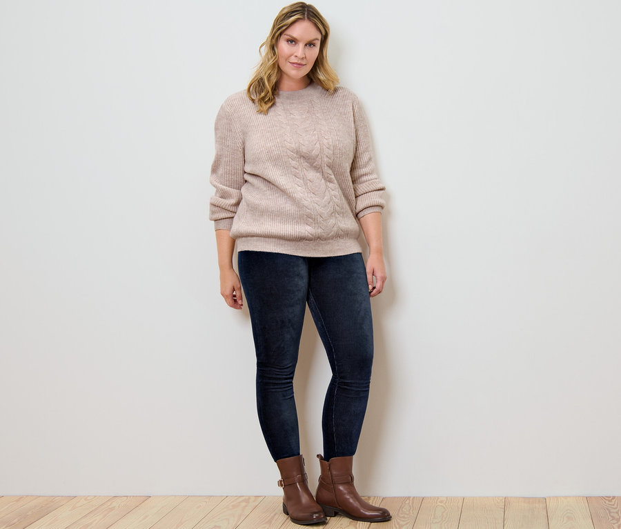 Femme posant en pull en grosse maille à motif torsadé et leggings en velours côtelé.