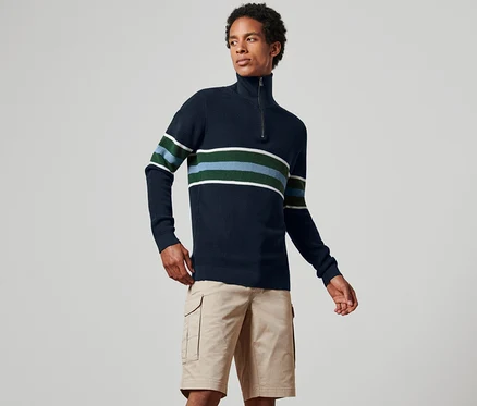 Un homme porte un pull camionneur bleu marine à rayures avec un short kaki.