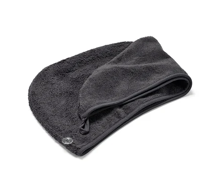 Une serviette turban anthracite est posée pliée sur un fond blanc.