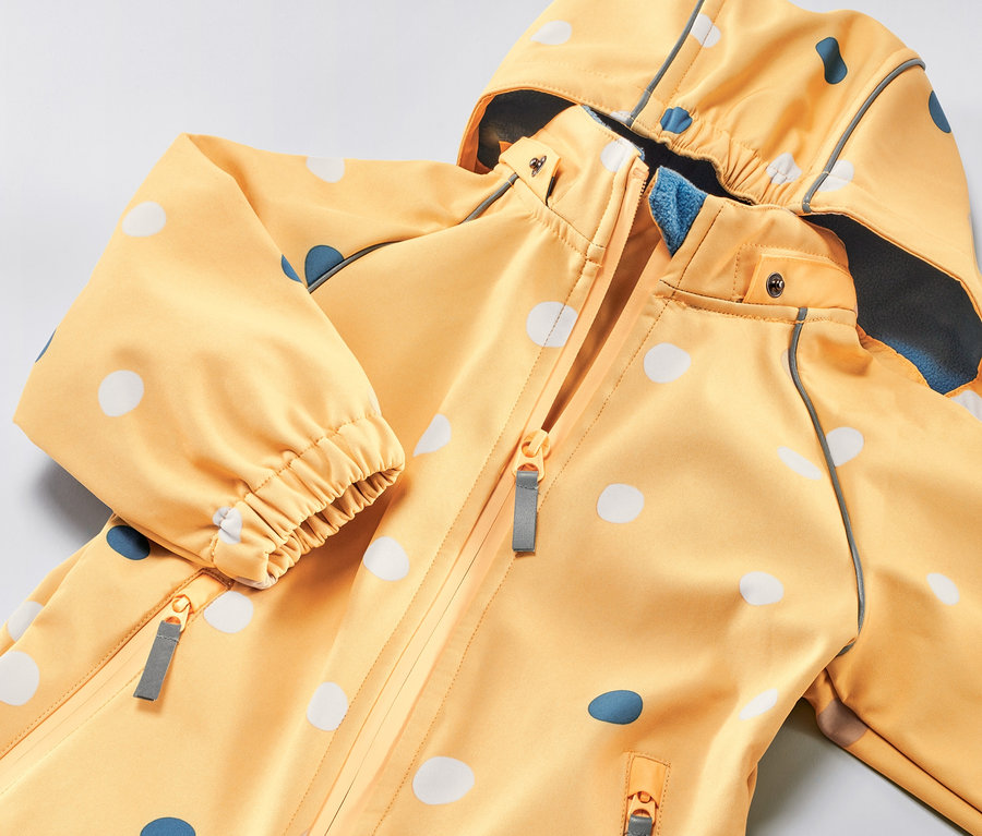 Combinaison softshell jaune orangé pour enfant avec un imprimé intégral à pois.