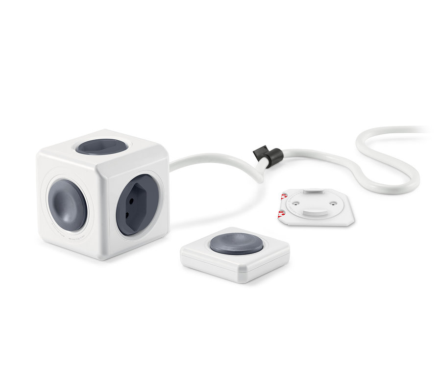 Un adaptateur secteur blanc en forme de cube avec quatre prises et deux télécommandes.