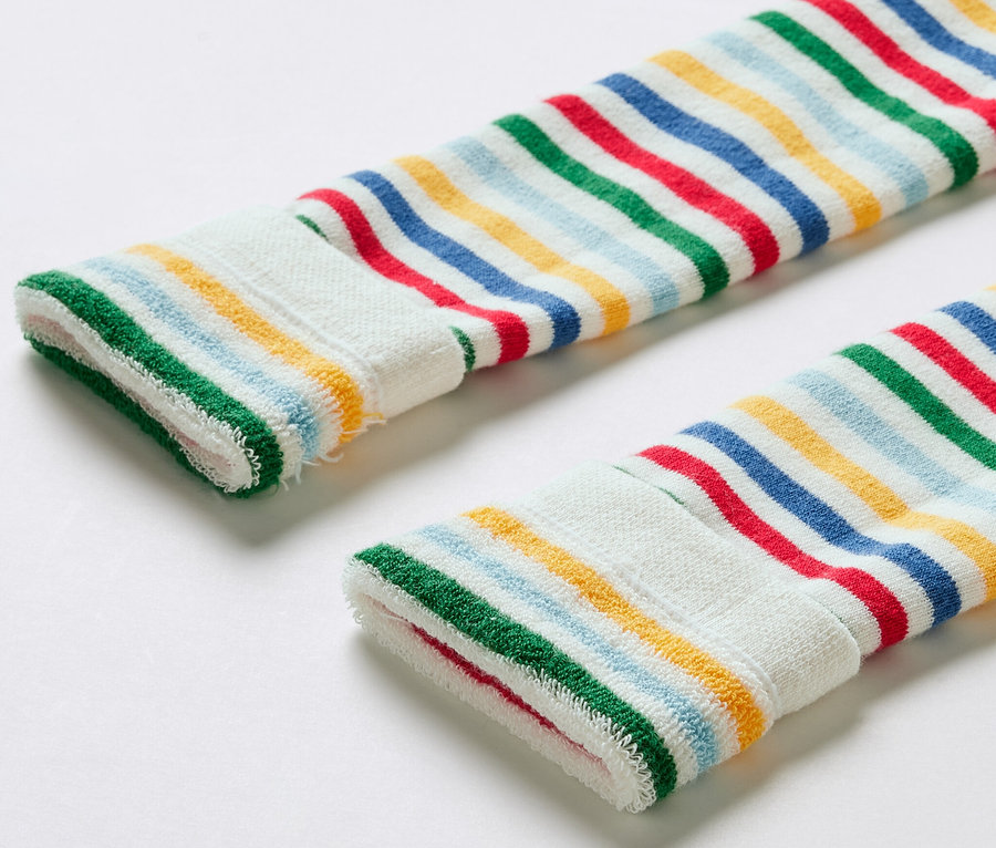 Gros plan sur trois leggings thermiques pour enfant à rayures colorées.