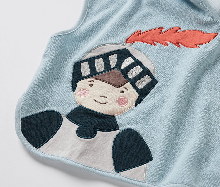 Gros plan sur un poncho en éponge bleu clair avec un motif de chevalier.