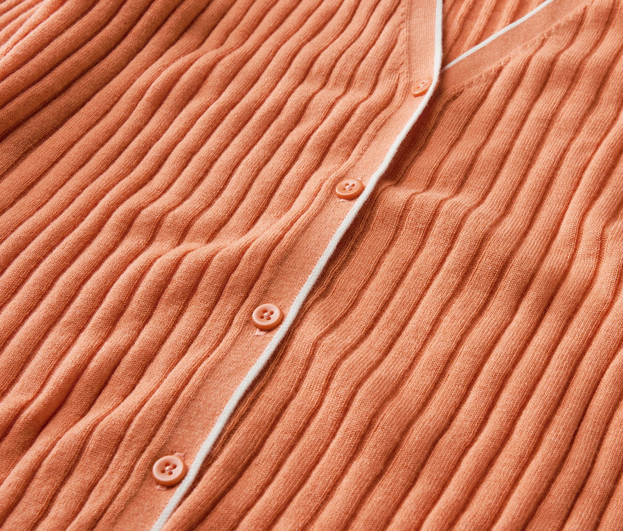 Gros plan sur un cardigan orange avec des boutons et de la soie.