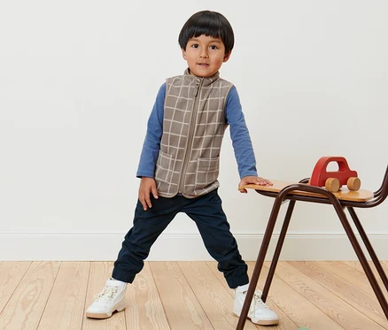 Garçon debout portant une veste polaire pour enfants à carreaux.