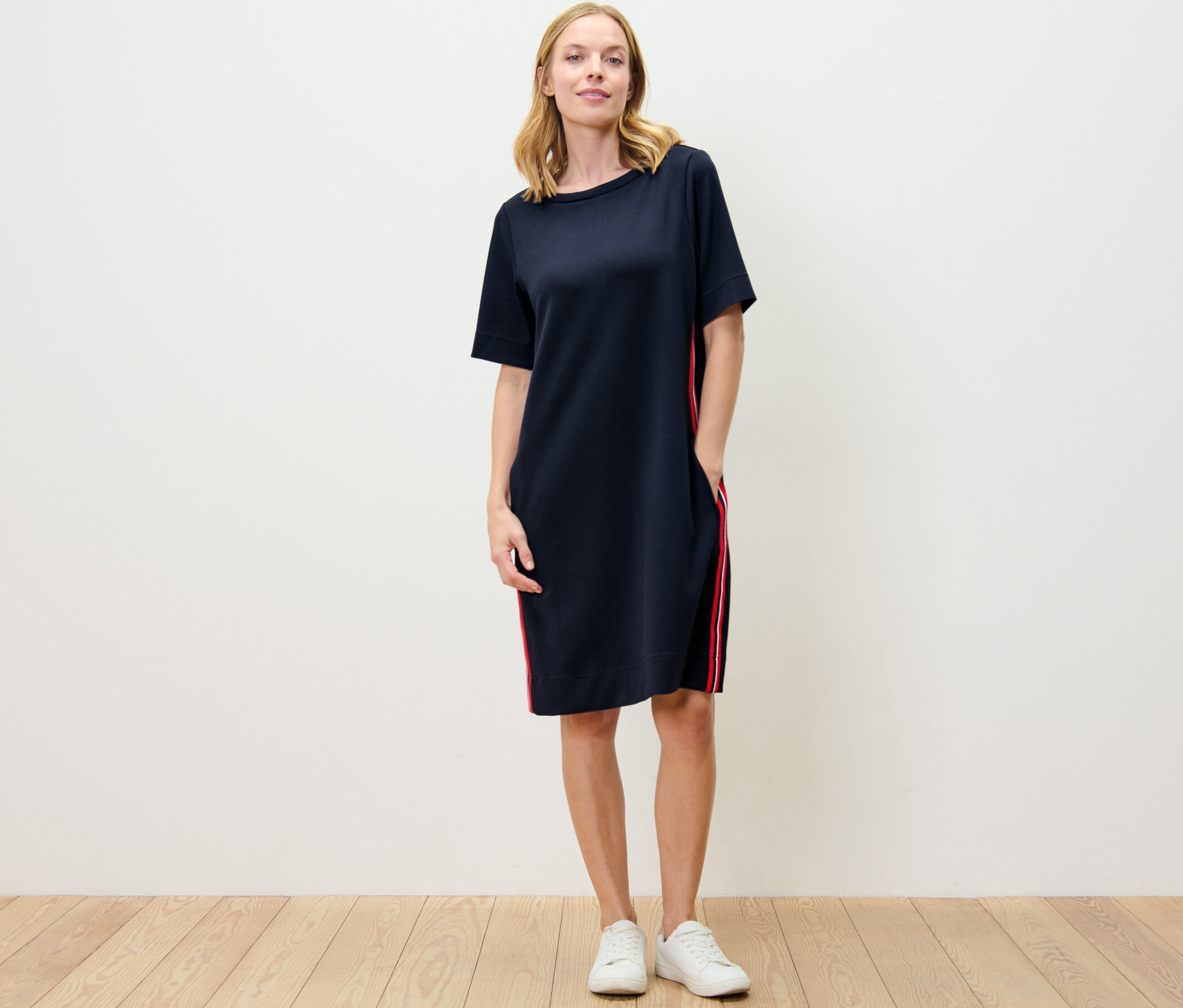 Une femme debout porte une robe en sweat à galons.