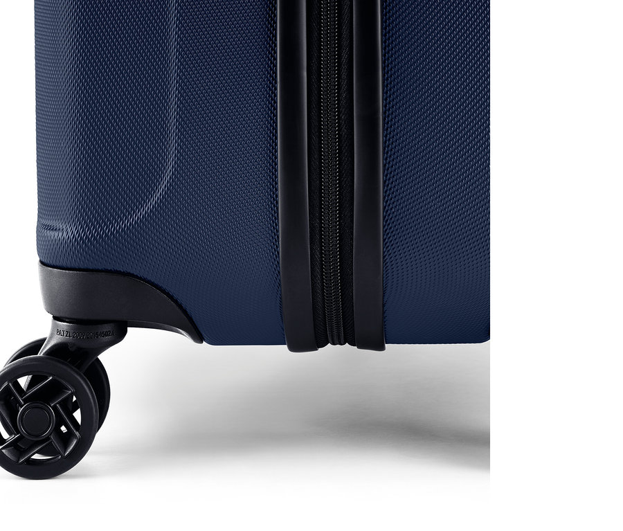 Détail d'une valise rigide bleue avec fermeture éclair et roulettes.