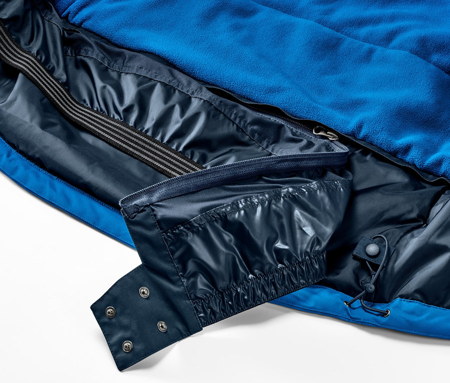 Gros plan sur une veste de ski pour enfant, montrant les poches intérieures et la fermeture.