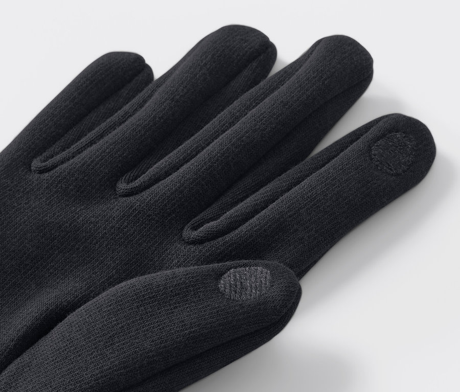 Gros plan de gants en sweat noirs sur fond clair.