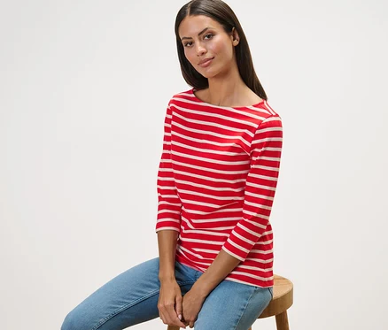 Femme assise sur un tabouret portant un t-shirt rayé manches 3/4, à rayures rouge.