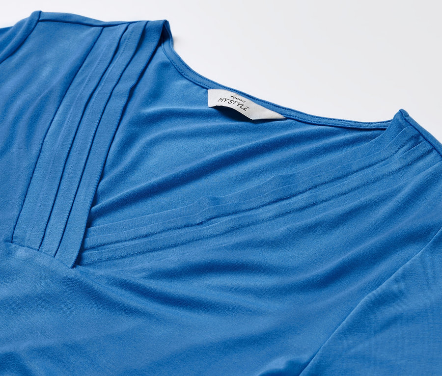 Gros plan d'un t-shirt bleu cobalt avec un détail de soufflet.