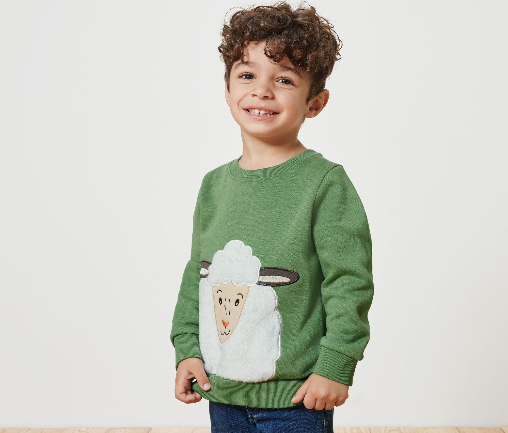 Garçon souriant portant un sweatshirt pour enfant avec intérieur gratté et un motif de mouton.