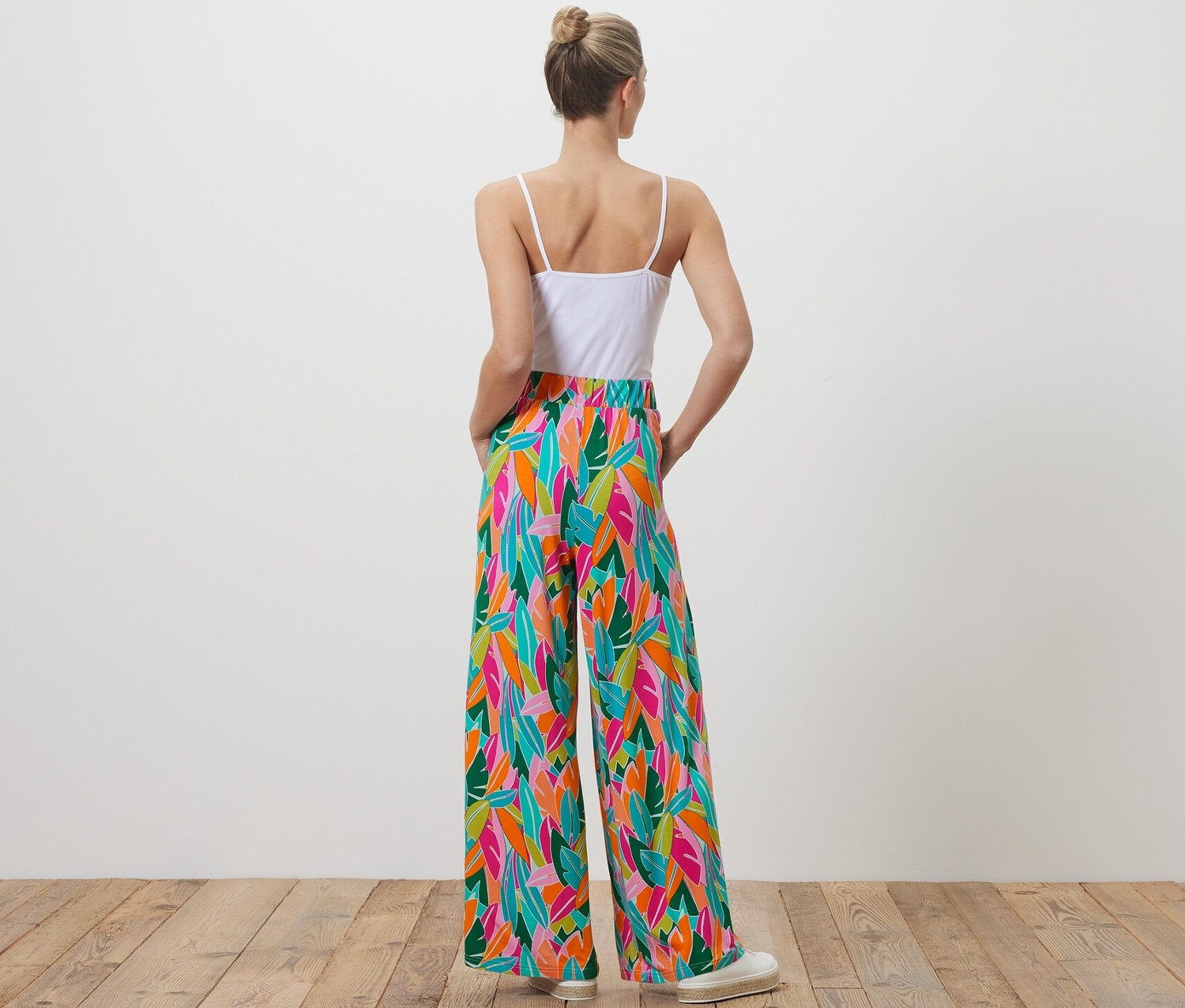 Une femme, vue de dos, porte un pantalon palazzo imprimé multicolore.