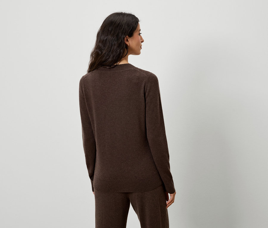 Femme posant en pull et pantalon marron.