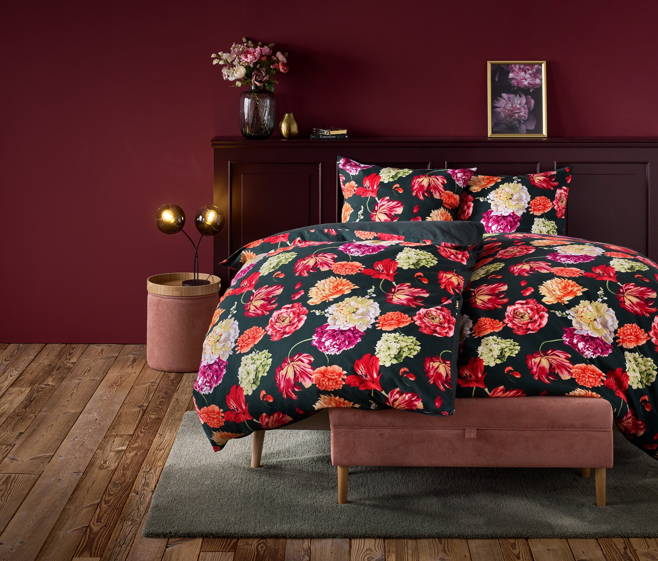 Linge de lit à fleurs sur un lit dans une pièce aux murs rouge bordeaux.