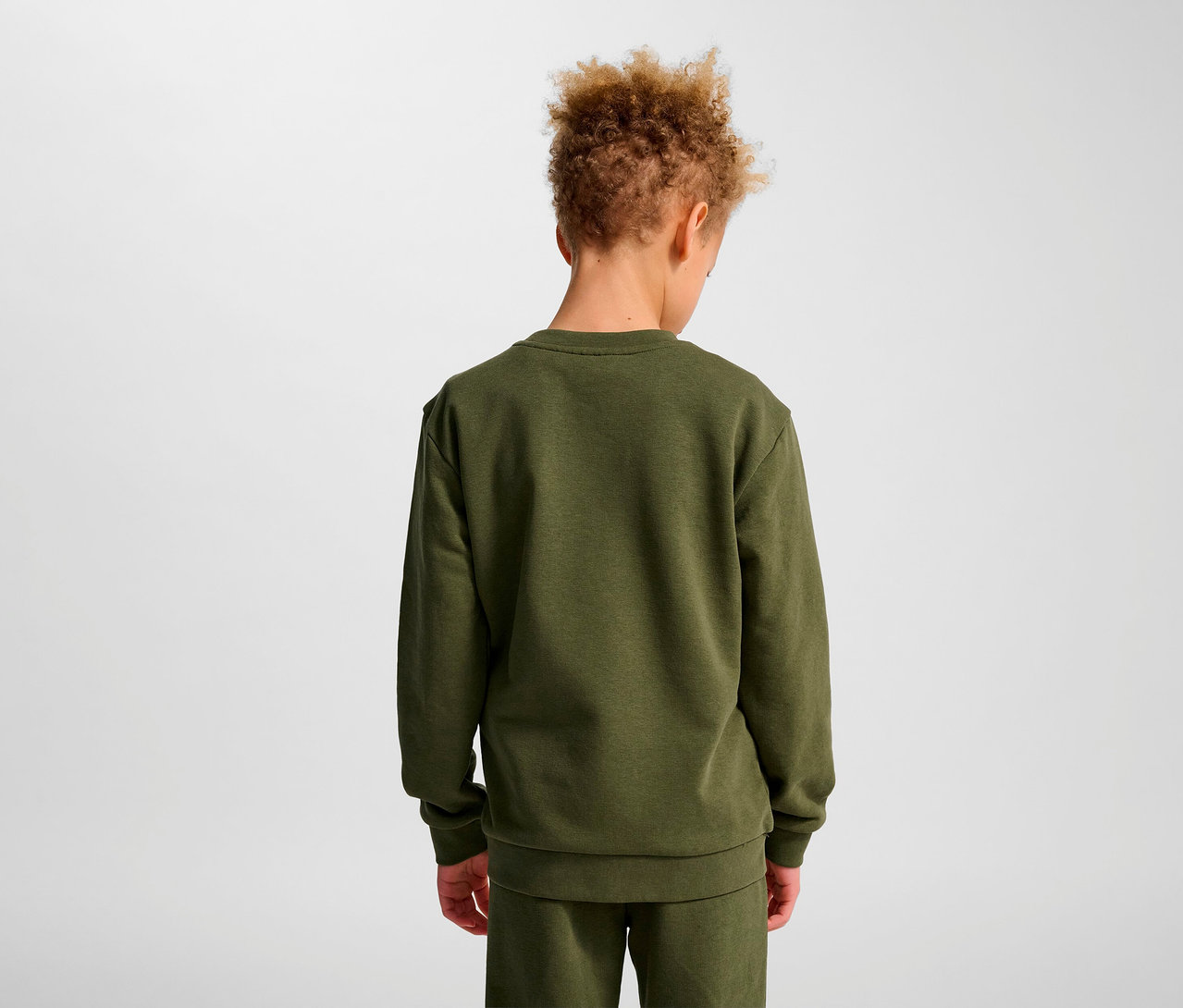 Garçon vu de dos portant un sweat-shirt HUMMEL HMLJR Base vert.