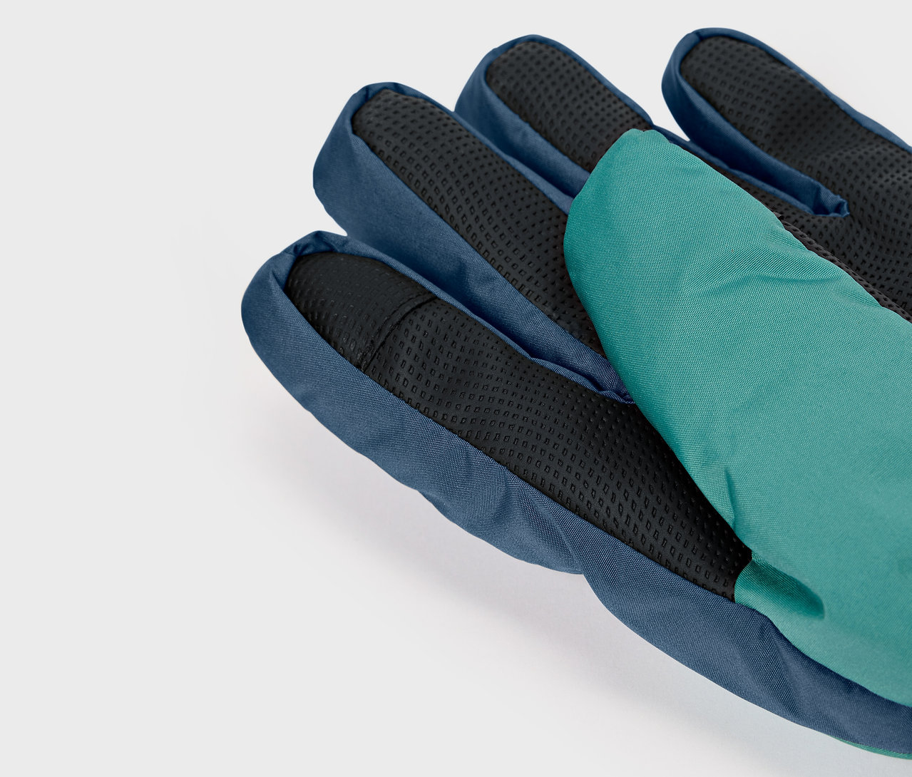 Gros plan d'un gant bleu avec une paume noire et un doigt vert.