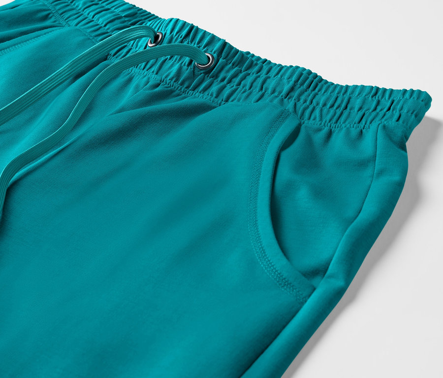 Détail d'un pantalon sweat 3/4 turquoise avec une taille élastique et un cordon de serrage.
