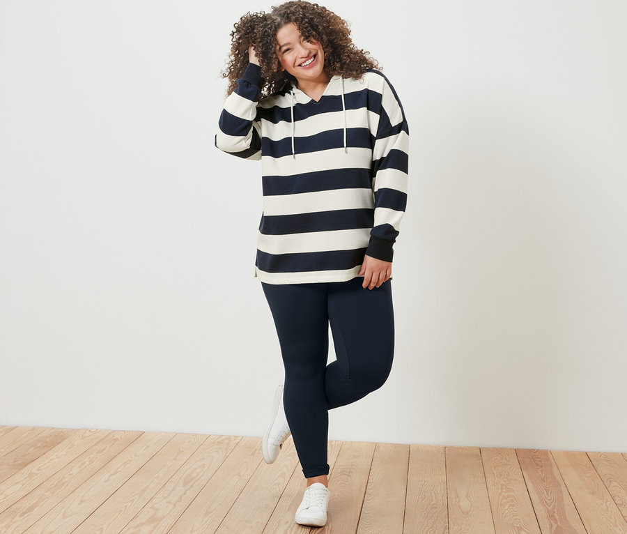 Femme posant en sweat à capuche à rayures et legging heavy.