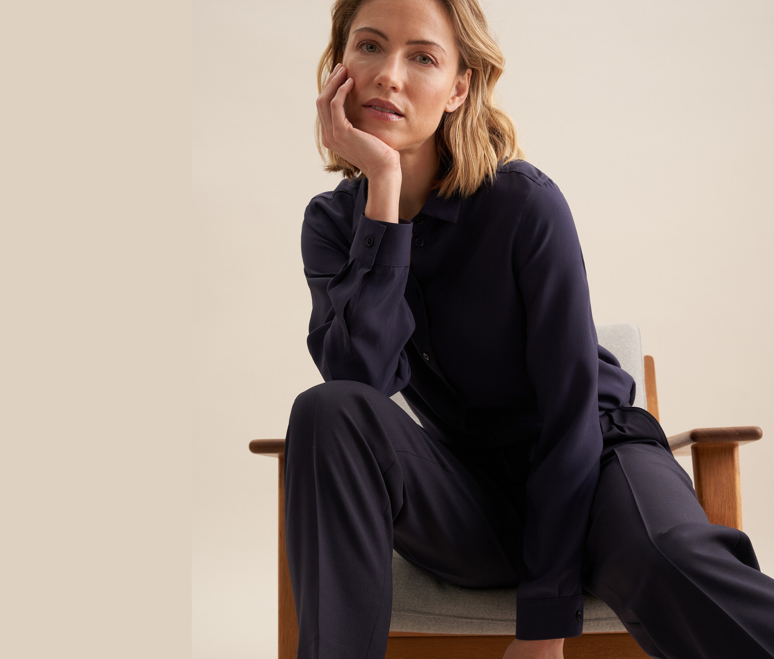 Une femme est assise sur une chaise et porte une chemise en viscose Seidensticker.