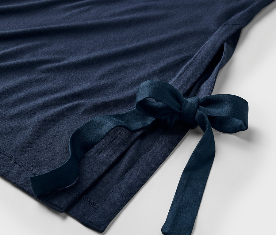 Détail d'une robe bleu marine avec un nœud sur le côté.