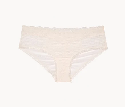 Une culotte couleur crème avec de la dentelle est posée sur un fond blanc.