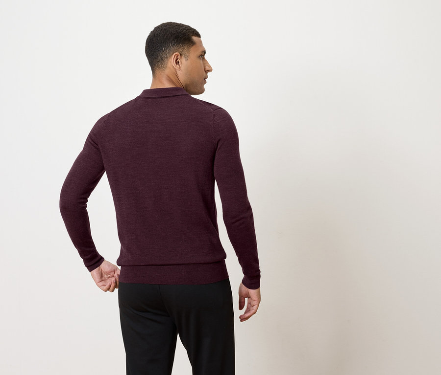 Homme portant un pull à manches longues bordeaux et un pantalon noir, regardant vers la gauche.