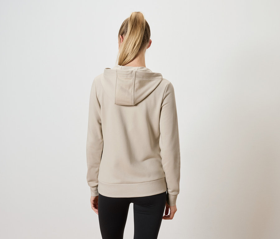 Vue de dos d'une femme aux cheveux blonds attachés en queue de cheval, portant un sweat à capuche beige et un pantalon noir.