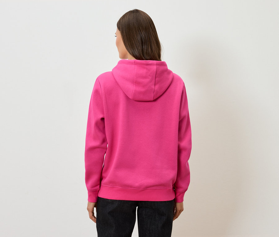 Vue arrière d'une femme aux cheveux bruns portant un sweat à capuche rose et un pantalon noir.