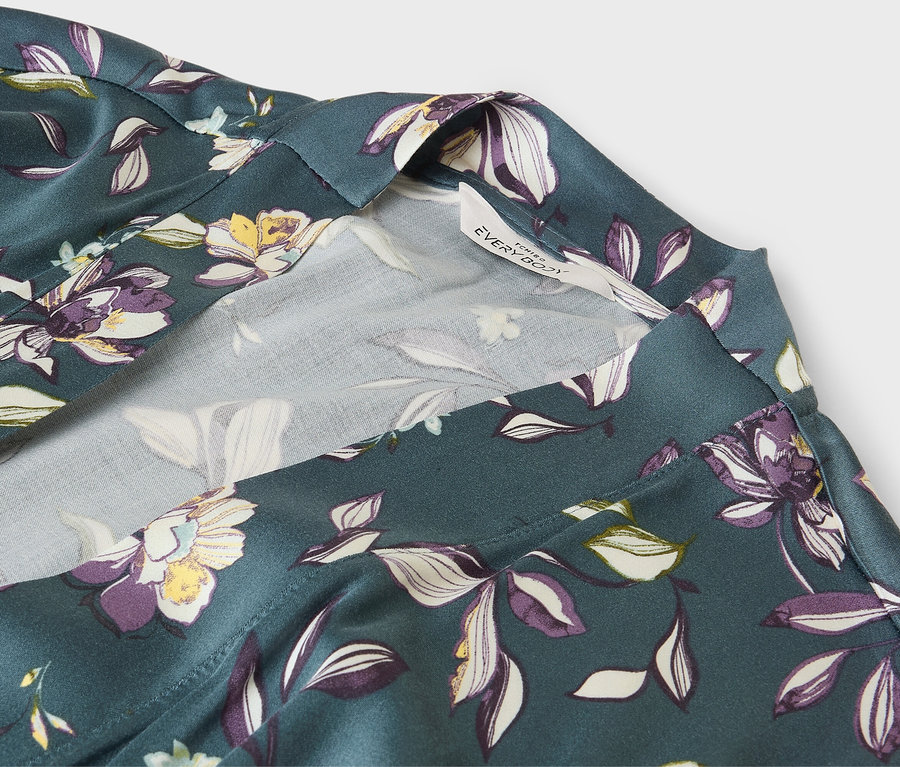 Gros plan sur un peignoir vert à motif floral avec une bordure blanche.