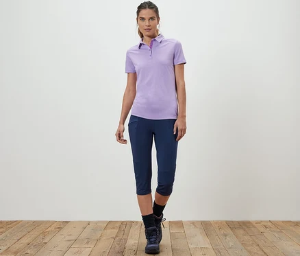 Femme posant en polo violet et legging de trekking 3/4.