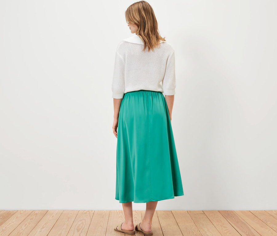 Femme debout de dos portant une jupe en satin.