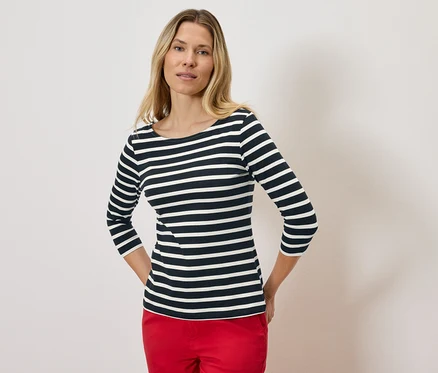 Blonde portant un t-shirt rayé à manches trois-quarts et un pantalon rouge.