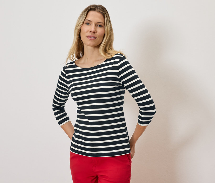 Blonde portant un t-shirt rayé à manches trois-quarts et un pantalon rouge.