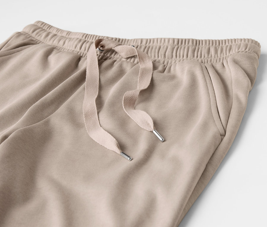 Gros plan sur un pantalon de survêtement beige avec cordon de serrage et poche.