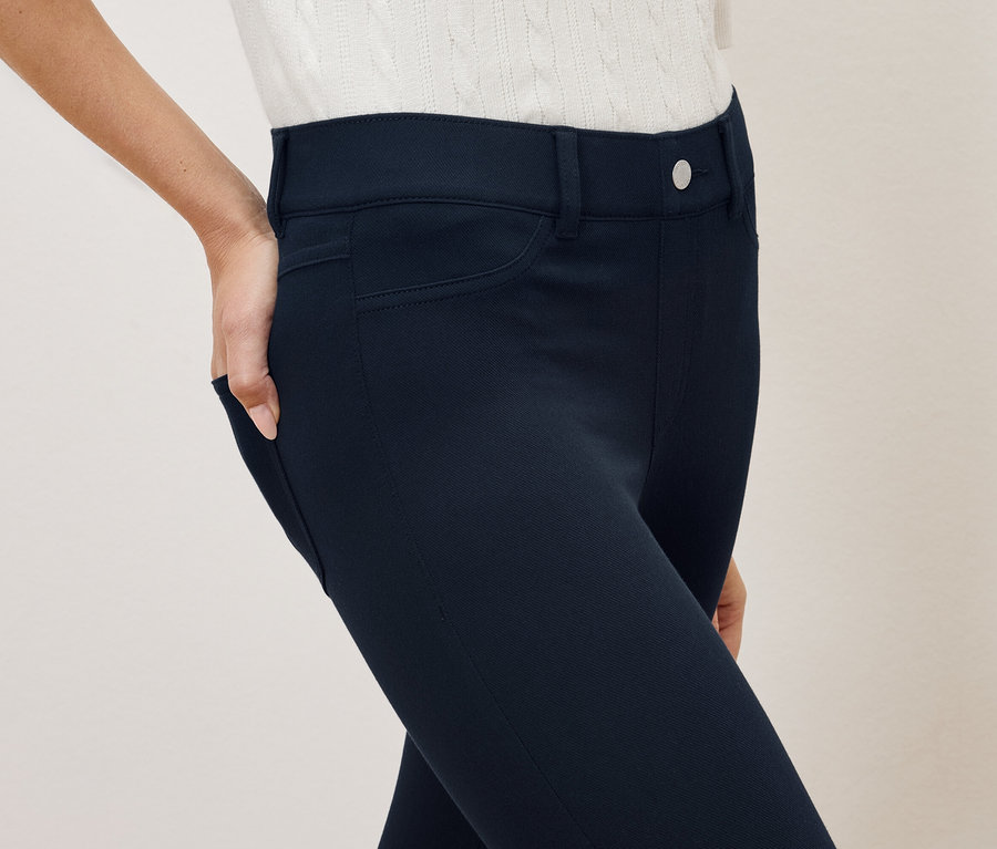 Une femme a la main dans la poche d'un pantalon bleu marine.