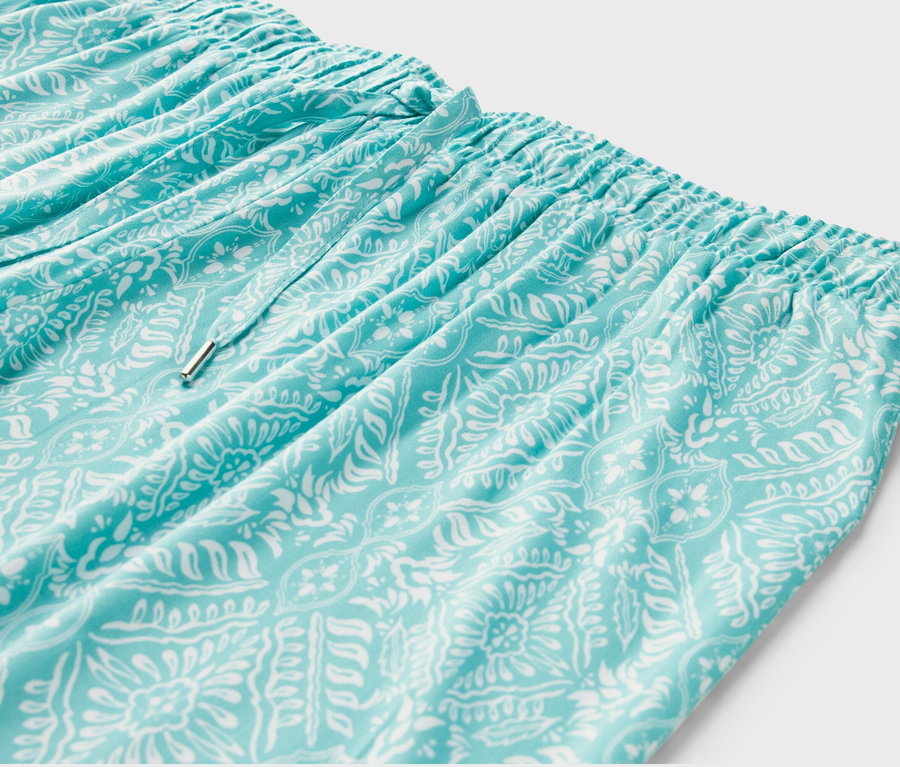 Détail d'un pantalon relax bleu clair avec un motif blanc.