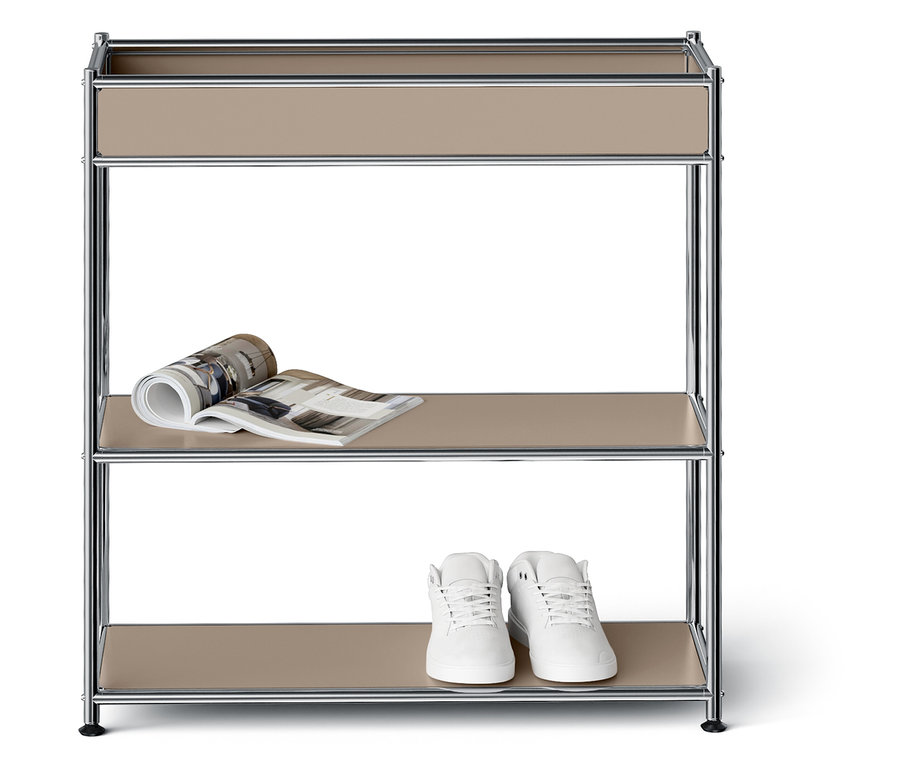 Étagère à trois niveaux avec un magazine sur l'étagère du milieu et des chaussures blanches sur l'étagère du bas.