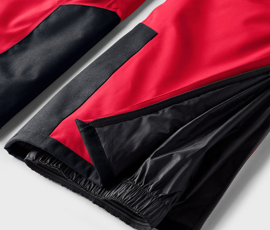 Gros plan sur un pantalon rouge et noir avec une fermeture éclair ouverte sur la jambe.