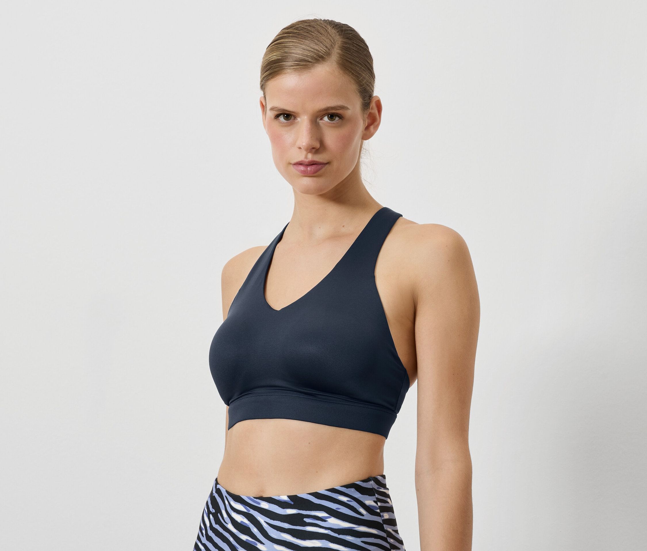 Une femme porte un soutien-gorge de sport bleu foncé et un legging à motif animal.