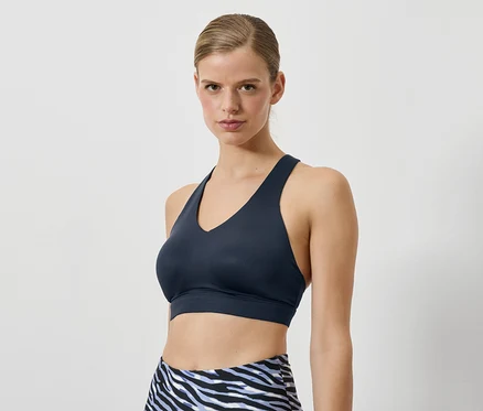 Une femme porte un soutien-gorge de sport bleu foncé et un legging à motif animal.