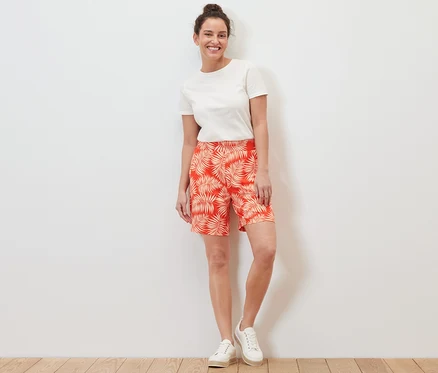 Une femme debout porte un short en jersey imprimé et un t-shirt blanc.