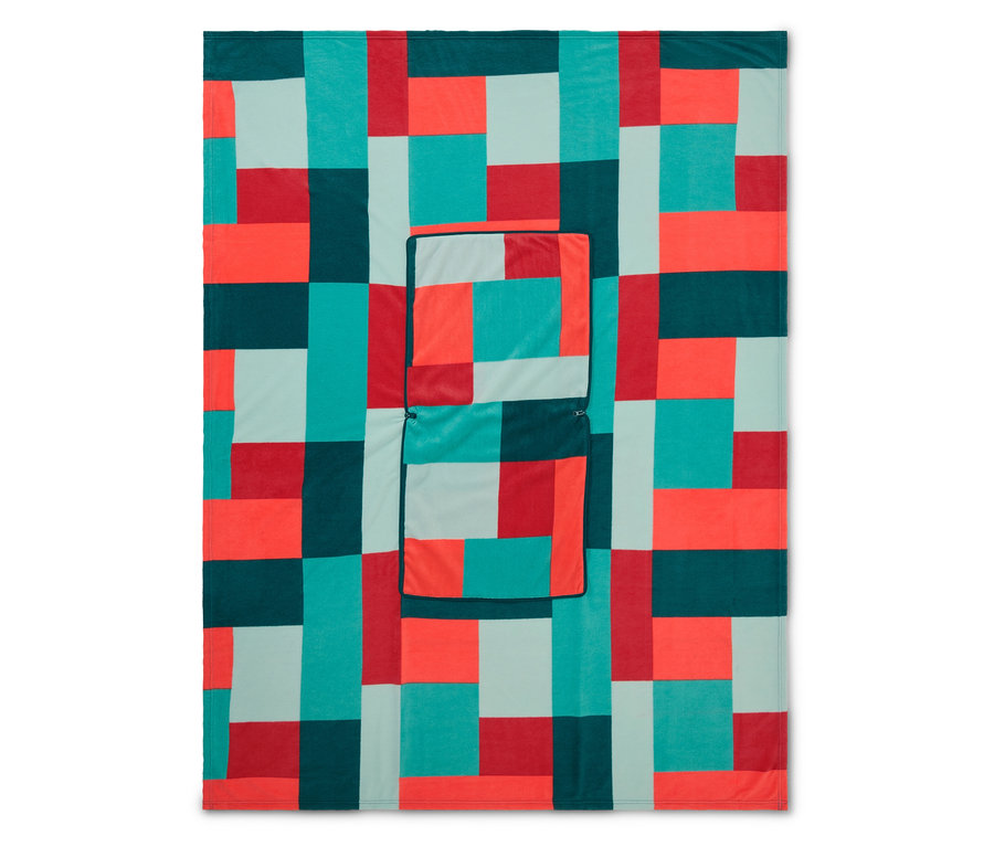Une couverture avec un motif géométrique de blocs rouges, turquoises, vert foncé et bleu clair, avec une poche cousue.