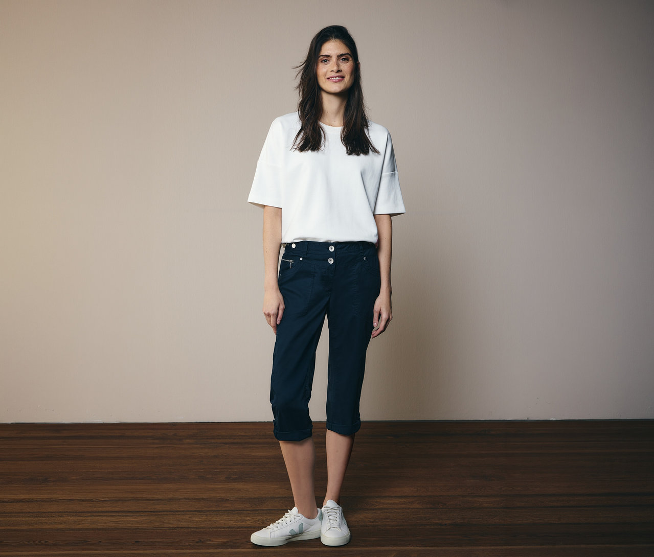 Femme portant un t-shirt blanc et un pantalon 3/4 Cecil «
New York
» bleu marine avec des baskets blanches.