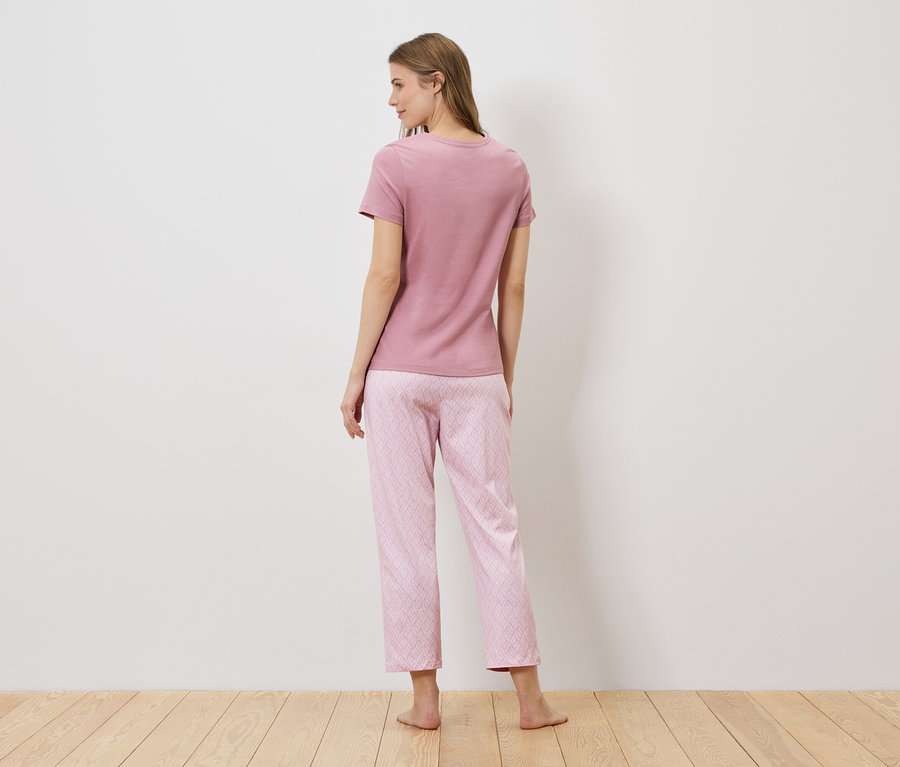 Vue arrière d'une femme aux cheveux longs portant un t-shirt rose et un pantalon de pyjama rose à motifs géométriques.
